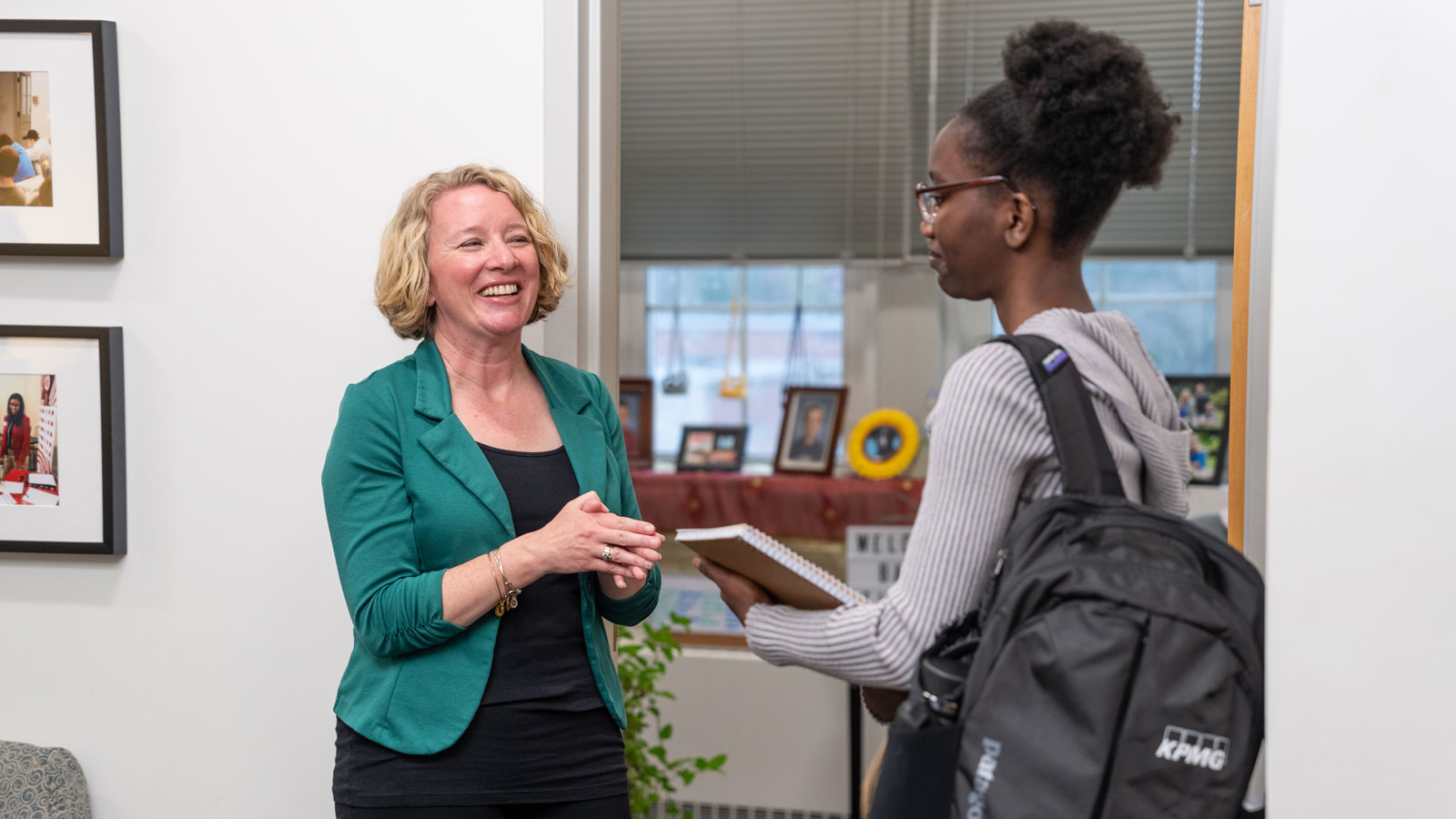 Student chats with an academic advisor outside of their office entrance