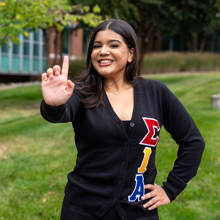 Alexandra Blandon making a hand sign for Hermandad de Sigma Iota Alpha, Inc