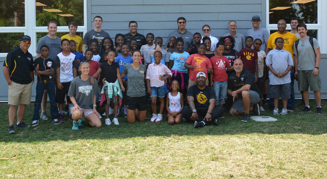 Coaches and staff members of the Towson University Athletics Department pose for a picture with fifth graders from the Living Classrooms Foundation summer camp in Fells Point. . 