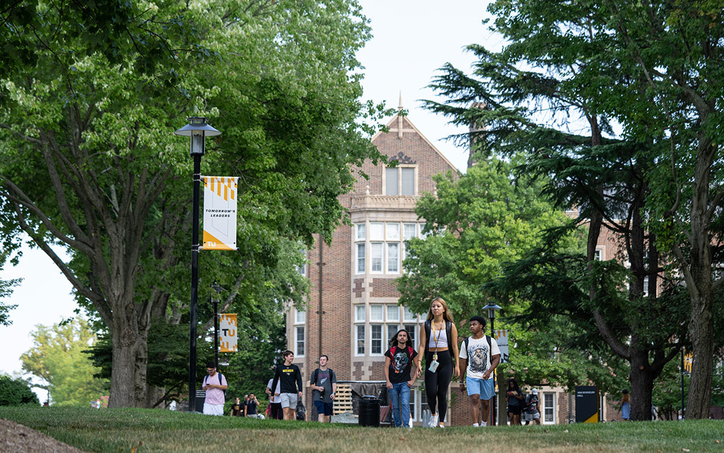 Students walking in front of trees, building
