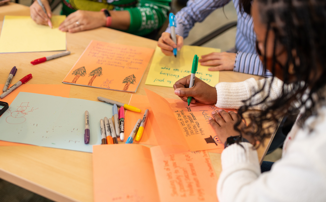 Volunteers write holiday cards for holiday packages