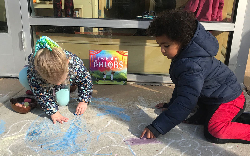 Two child care students draw with chalk