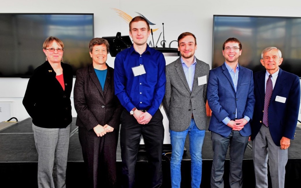 Six people in front of a stage