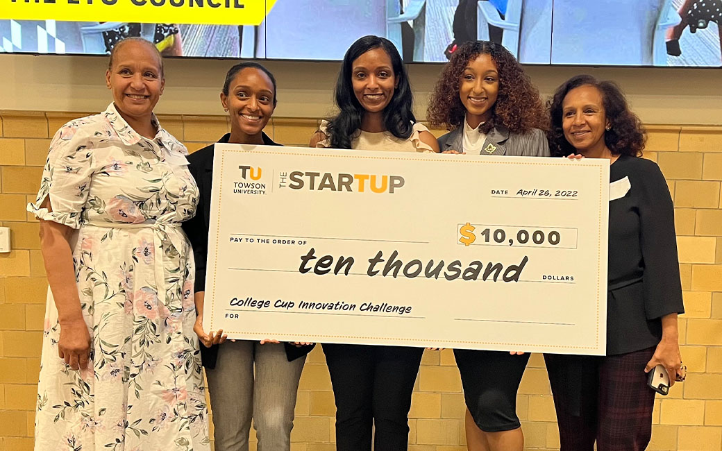 Women on stage holding giant check for $10,000