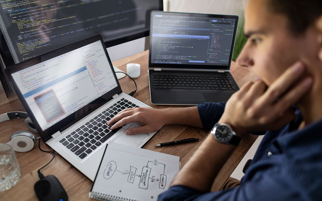 Man looking at computer screen and notebook