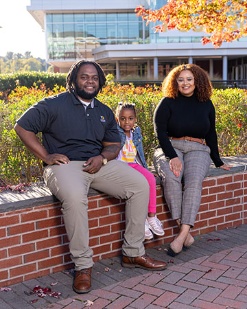 Dajaha Kenney, Ansel Stewart and Autumn Stewart sit on a wall in front of Burdick Hall