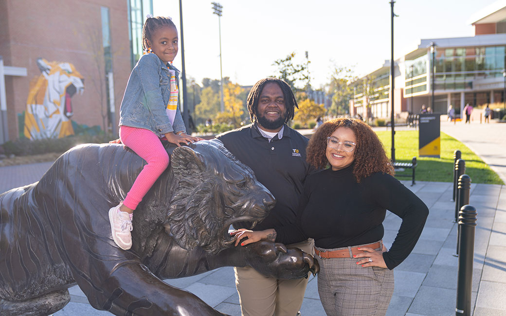 Dajaha Kenney and her family posing next to a tiger statue.