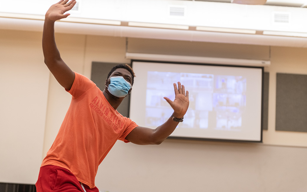 Masked dance instructor with Zoom class in background