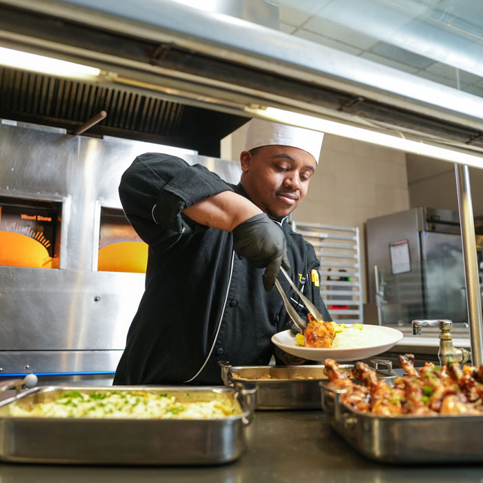 A TU Dining staff member serves food in one of the dining halls on campus