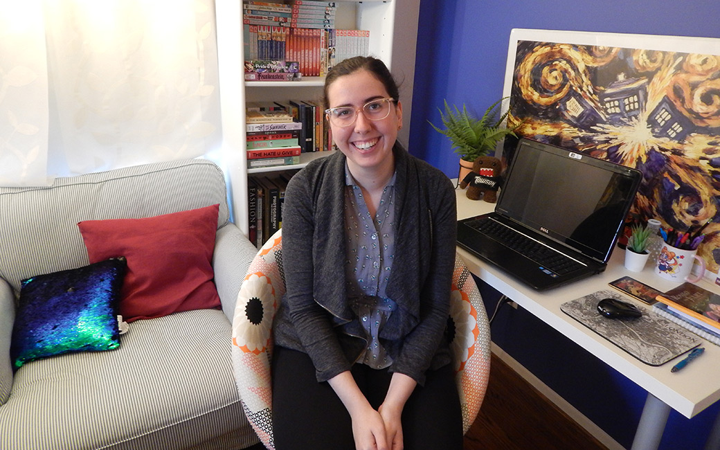 Intern teacher Emily Witt sitts at home virtual teaching setup at desk with laptop and books