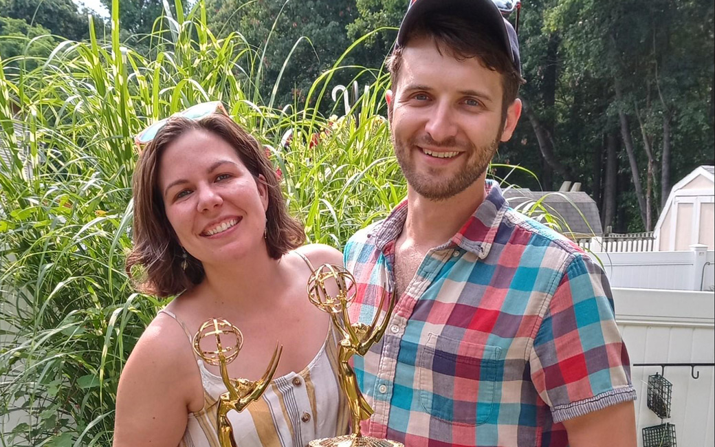 Jena Burchick, left and Mark Burchick, right, standing outside holding their Emmy awards.
