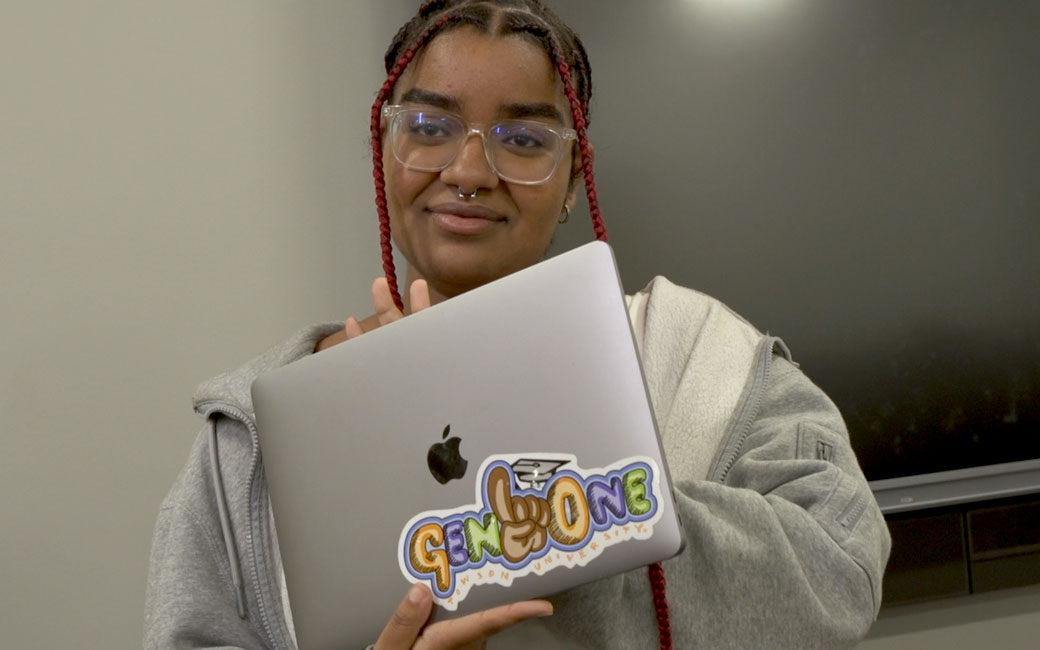 student holding laptop with first generation decal sticker on it
