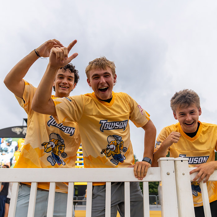 three students in gold jerseys excited at a TU football game