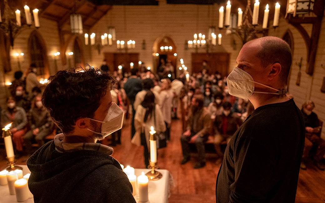 People wearing face coverings in church setting with candles