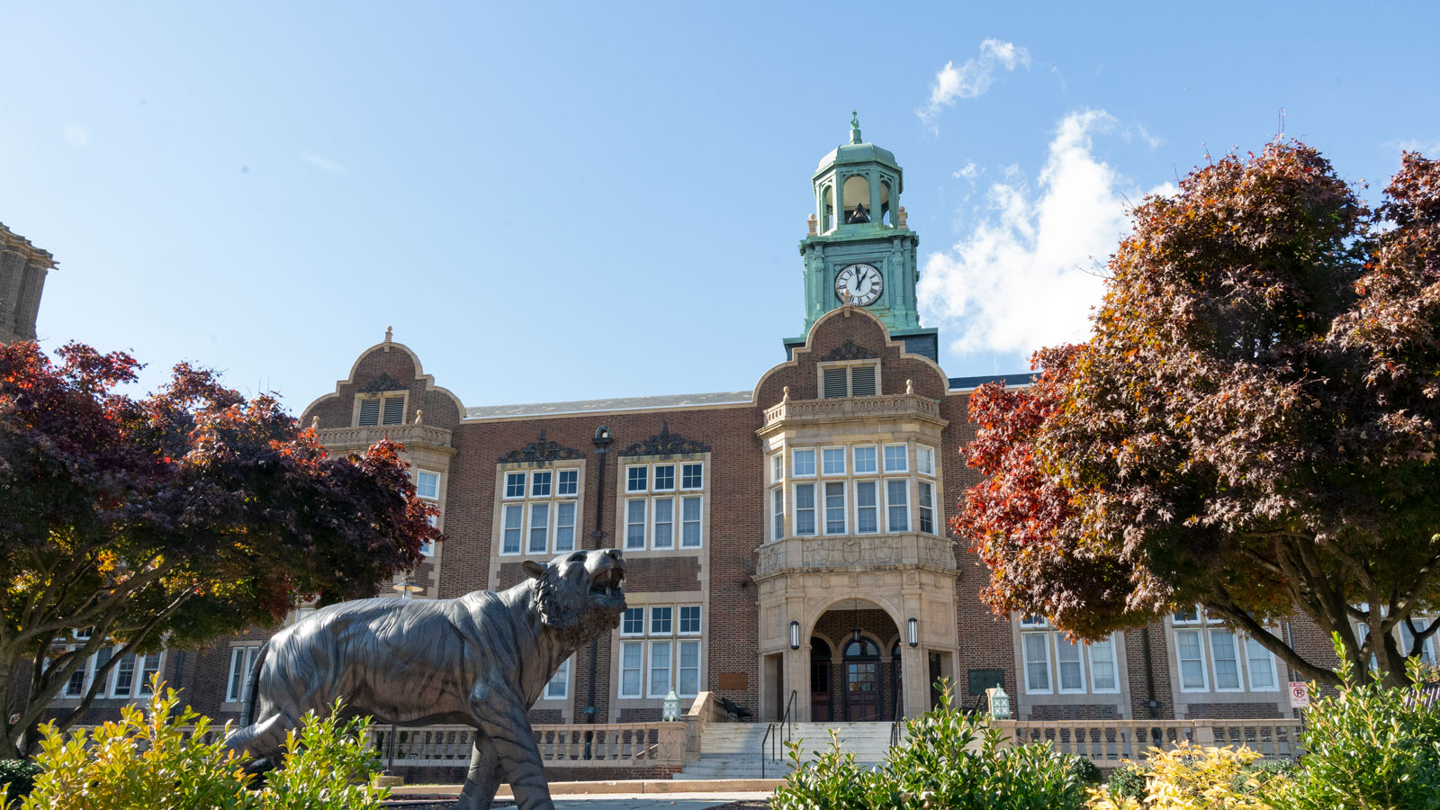 Front of Stephens Hall clock tower and Tiger statue on a clear blue day.