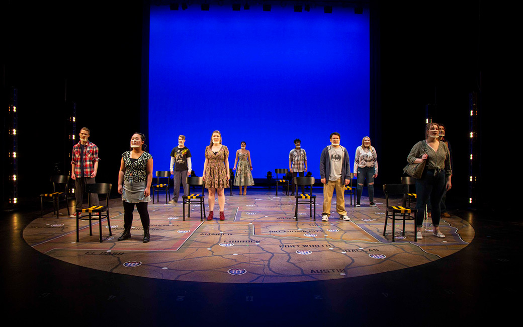 Students stand on a stage printed with a U.S. map