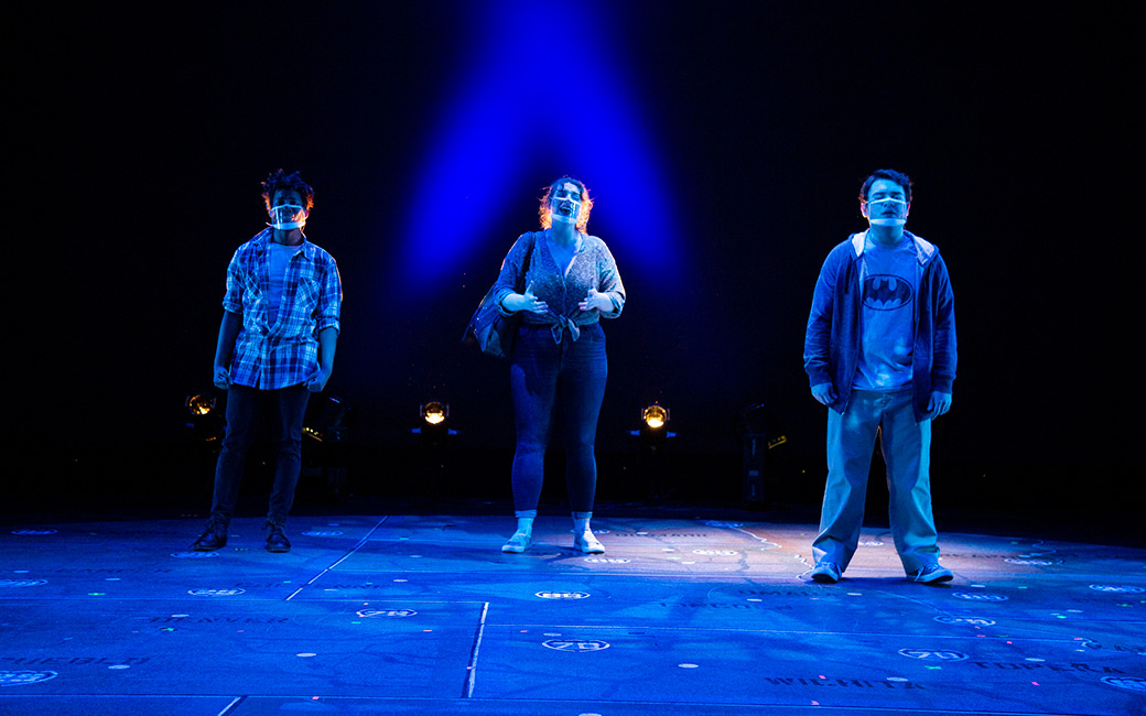 Three students on stage under blue light