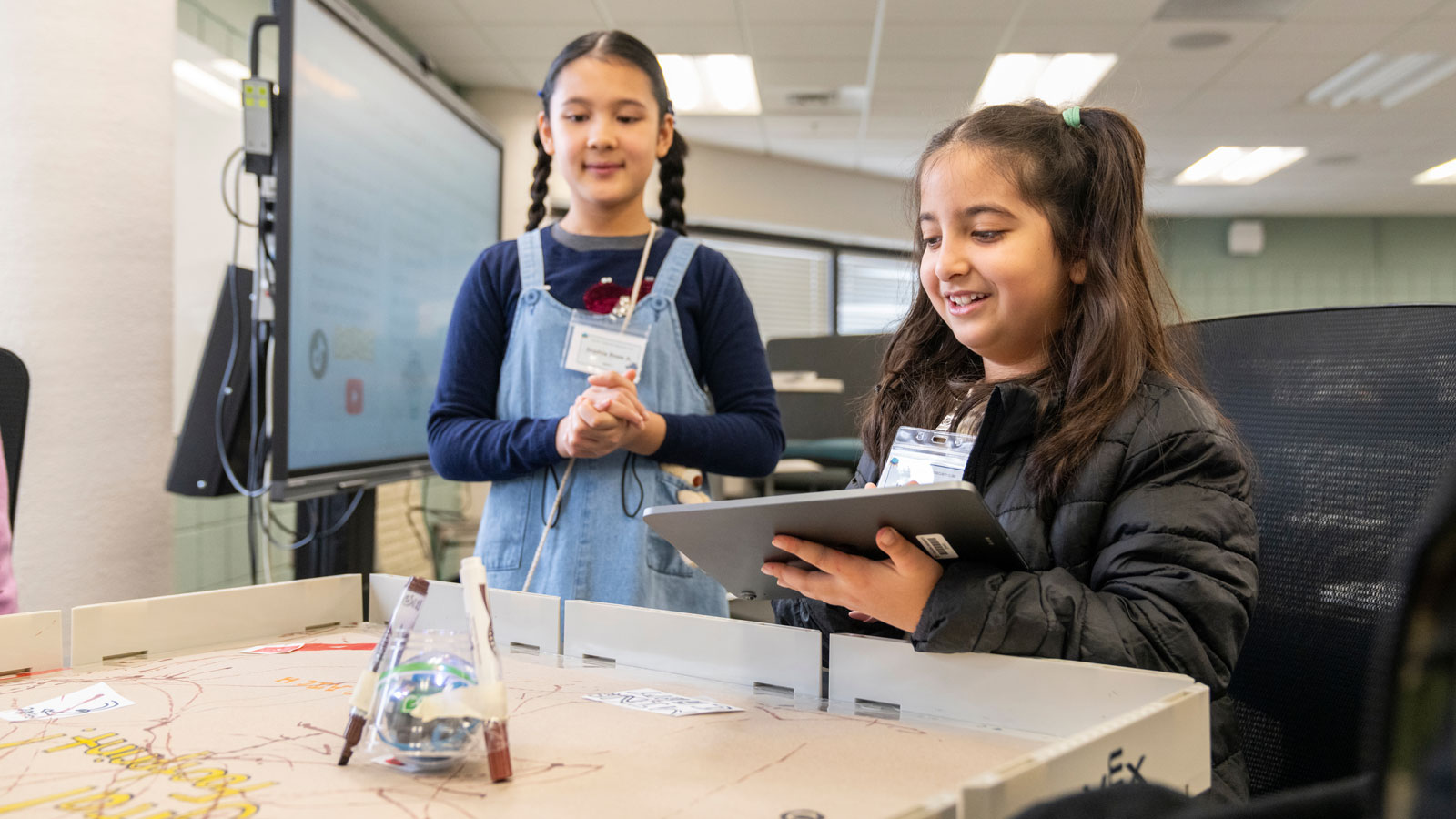 Two elementary students control a robot with an iPad. 