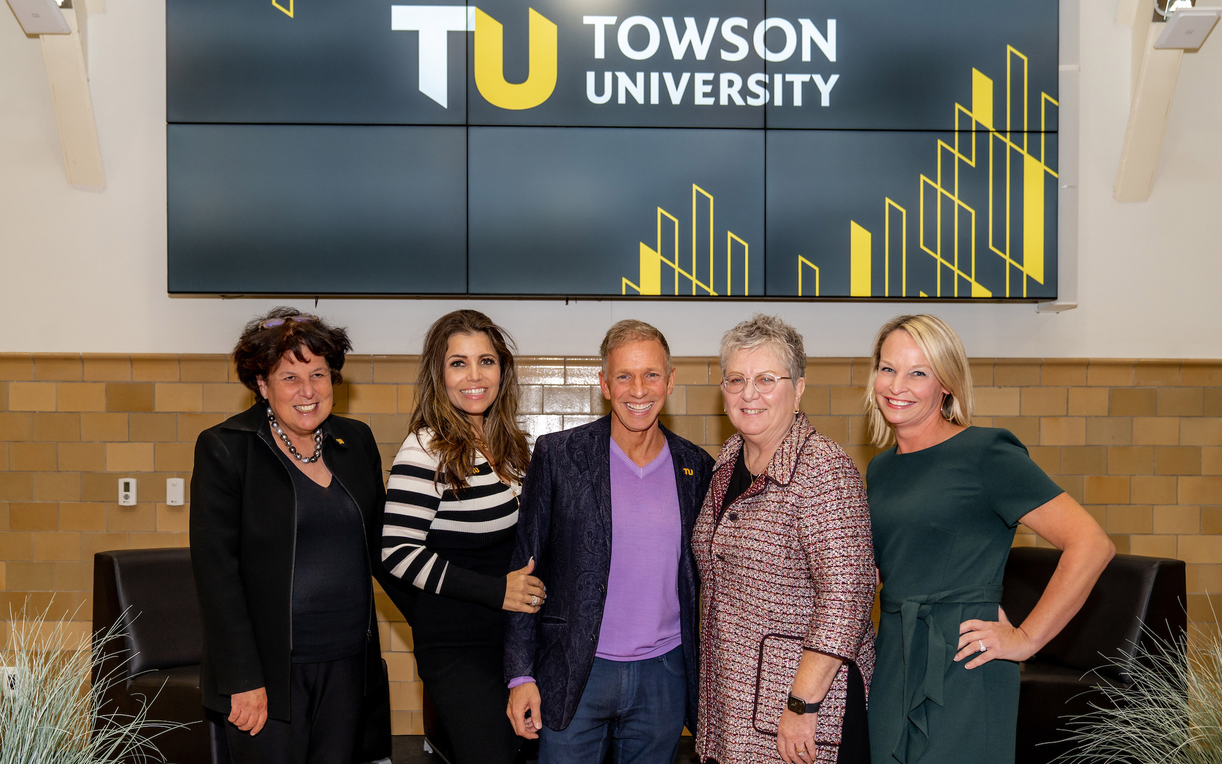 Group stands in front of digital screen with TU logo