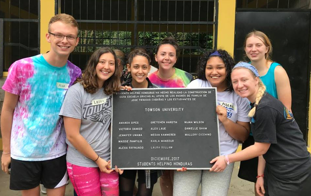 Members of the Towson University chapter of Students Helping Honduras hold up a special thank you sign they received while working in Arena Blanco, Honduras. 