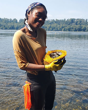 Brianna Hutchins '23 standing in water with oysters