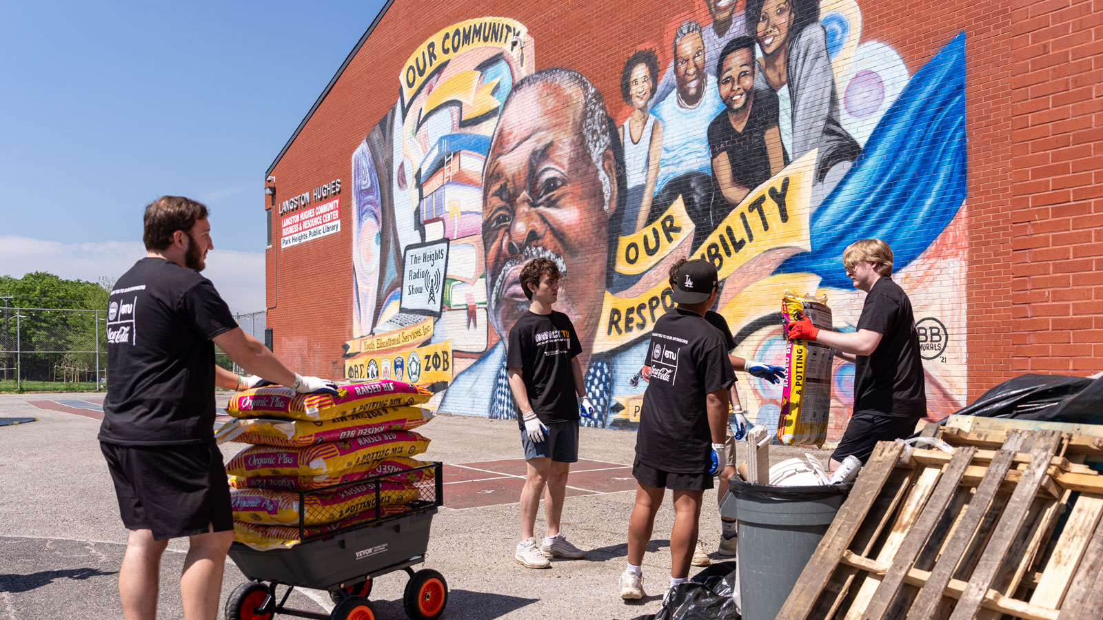 Fraternity members transport soil bags from the storage of the Langston Hughes Community, Business and Resource Center to their community garden