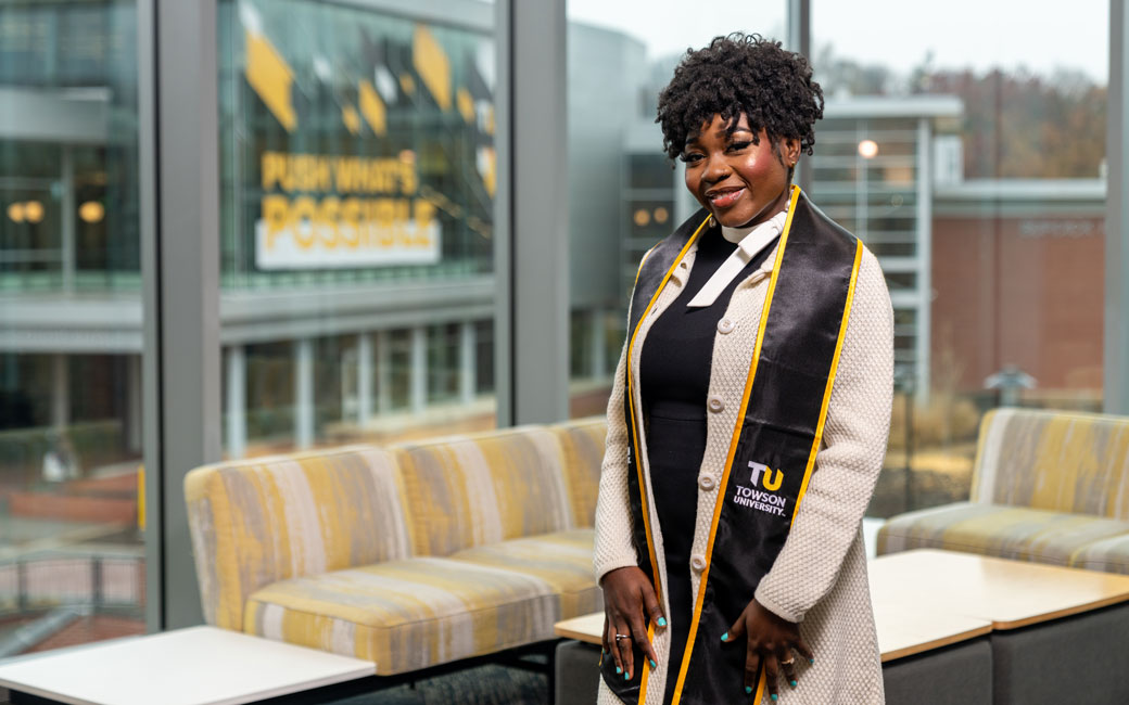 Woman student stand in University Union wearing commencement stole