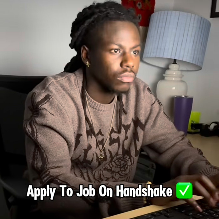 TU student on the computer with text overlay that says "apply to job on handshake"
