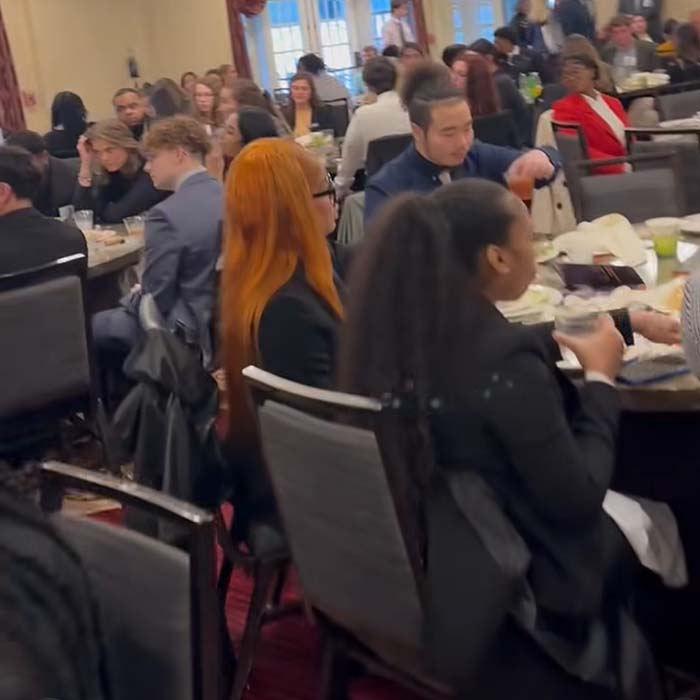 people sitting at tables in a large room eating