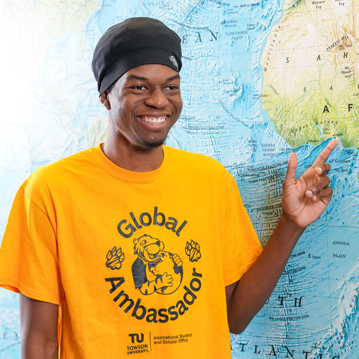 King gestures to his home city of Lagos, Nigeria on a world map in the Liberal Arts Building