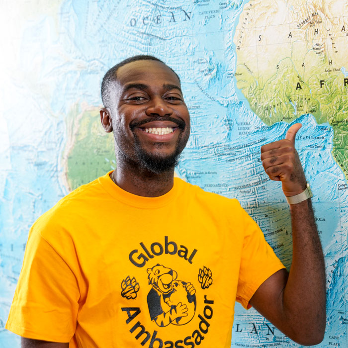 Osazee points to his home of Lagos, Nigeria on a world map in the Liberal Arts Building