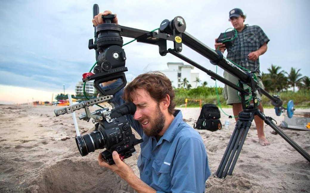 Cinematographer John Benam filming on a beach