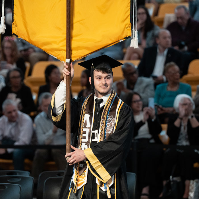 Konner Thomas carrying the CBE banner at commencement