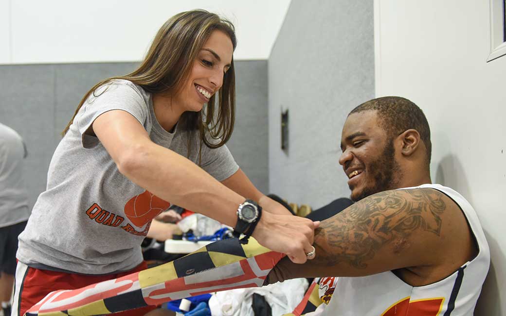 Laura Karp helps Maryland Mayhem player Randy Johnson get ready for quad rugby practice.