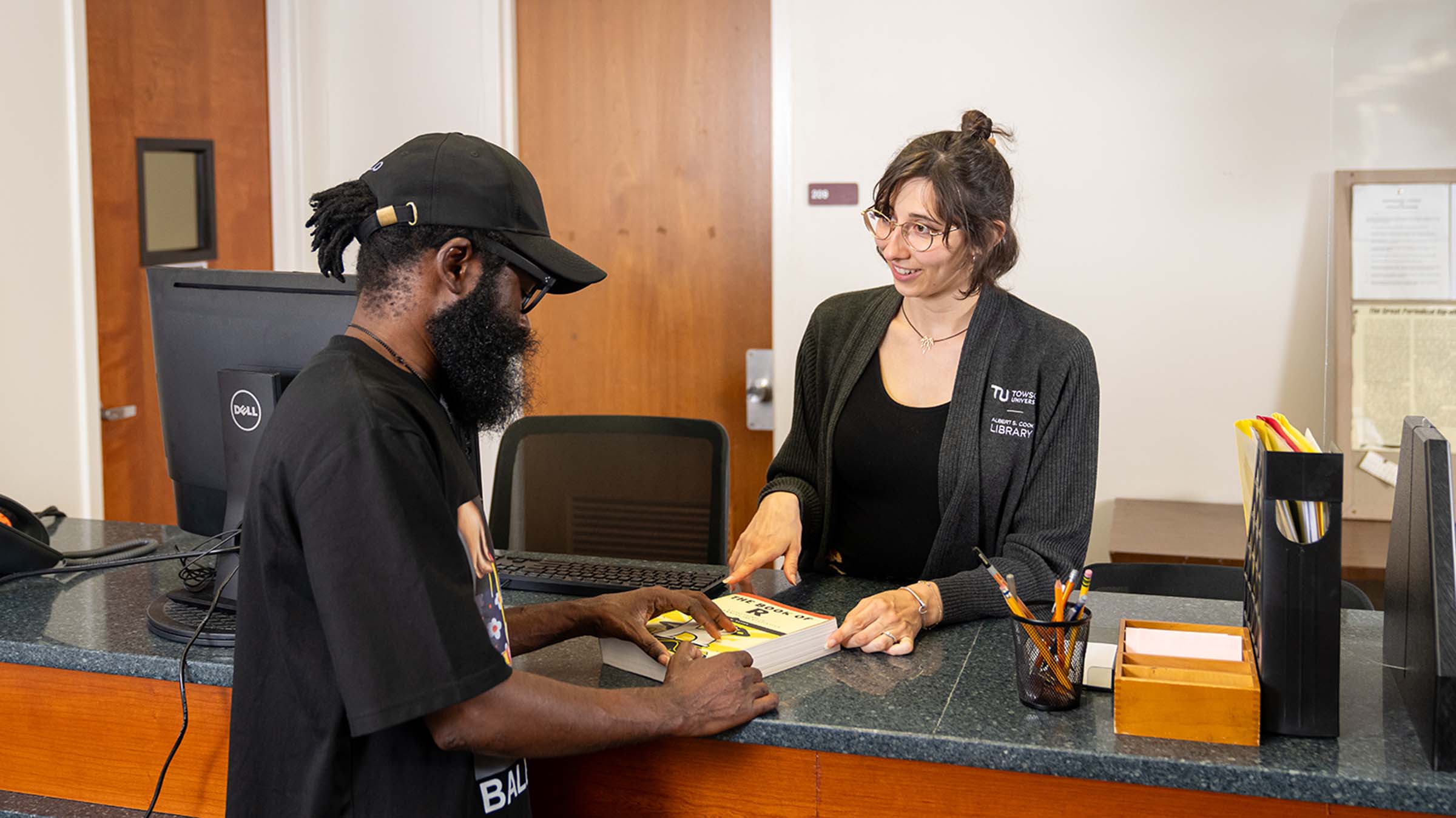 student checking out a book at Cook Library