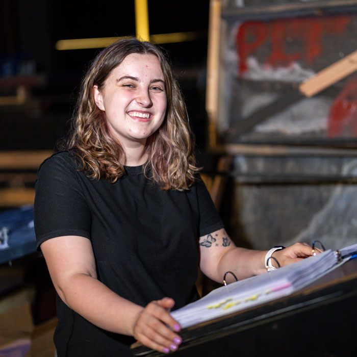 Magen Cornacchione, stage manager for TU's production of 1776, holds her binder backstage