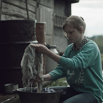 Film still of woman washing in bucket