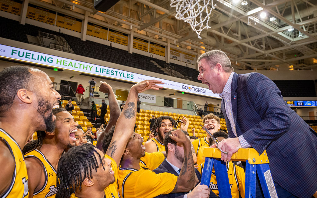 Men's basketball coach Pat Skerry celebrates with team after winning CAA Championship