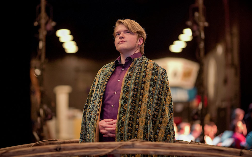 Portrait of man wearing cape stands backstage