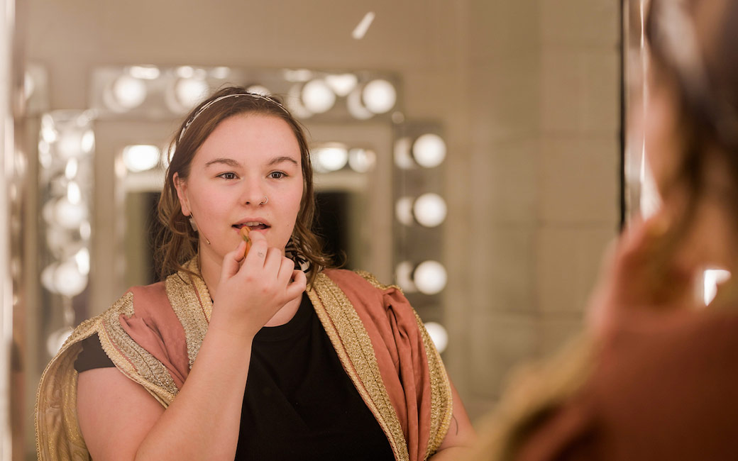 Woman looking in mirror applies makeup