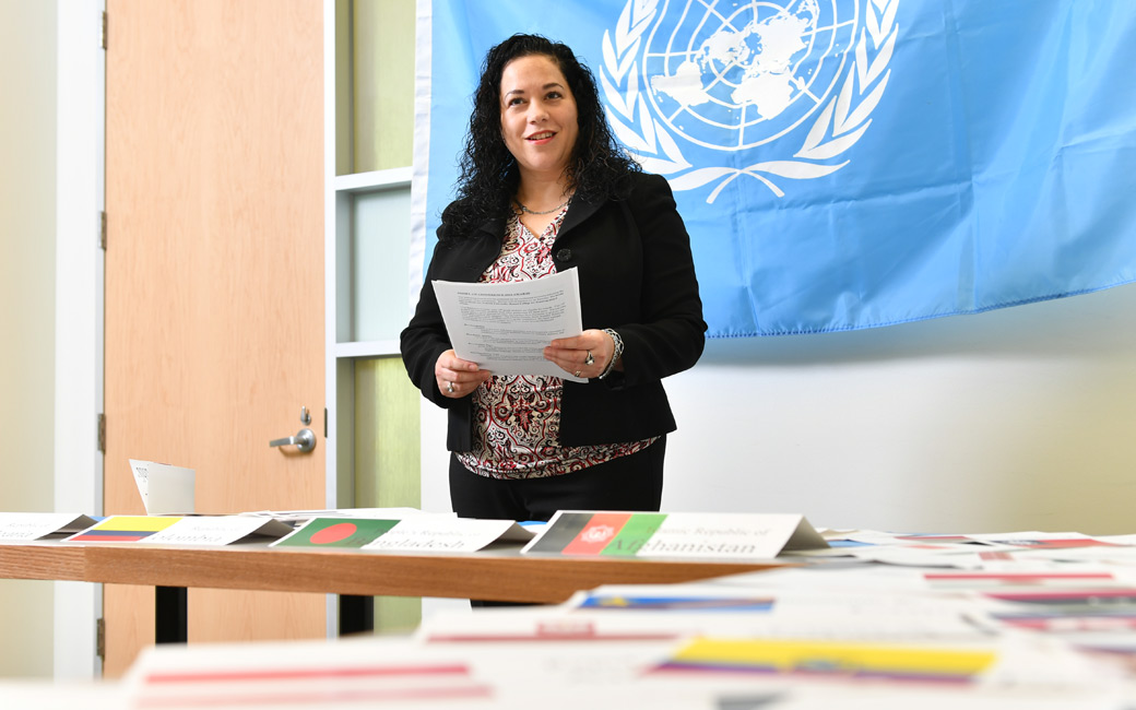 Alison McCartney standing in front of the flag of the United Nations