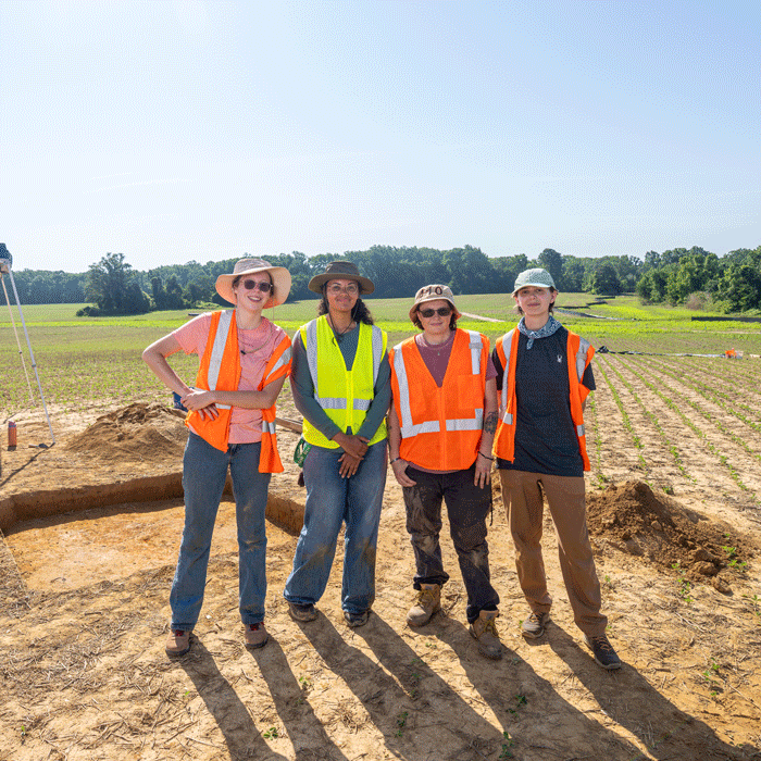 Four students researchers at an archaeological dig site