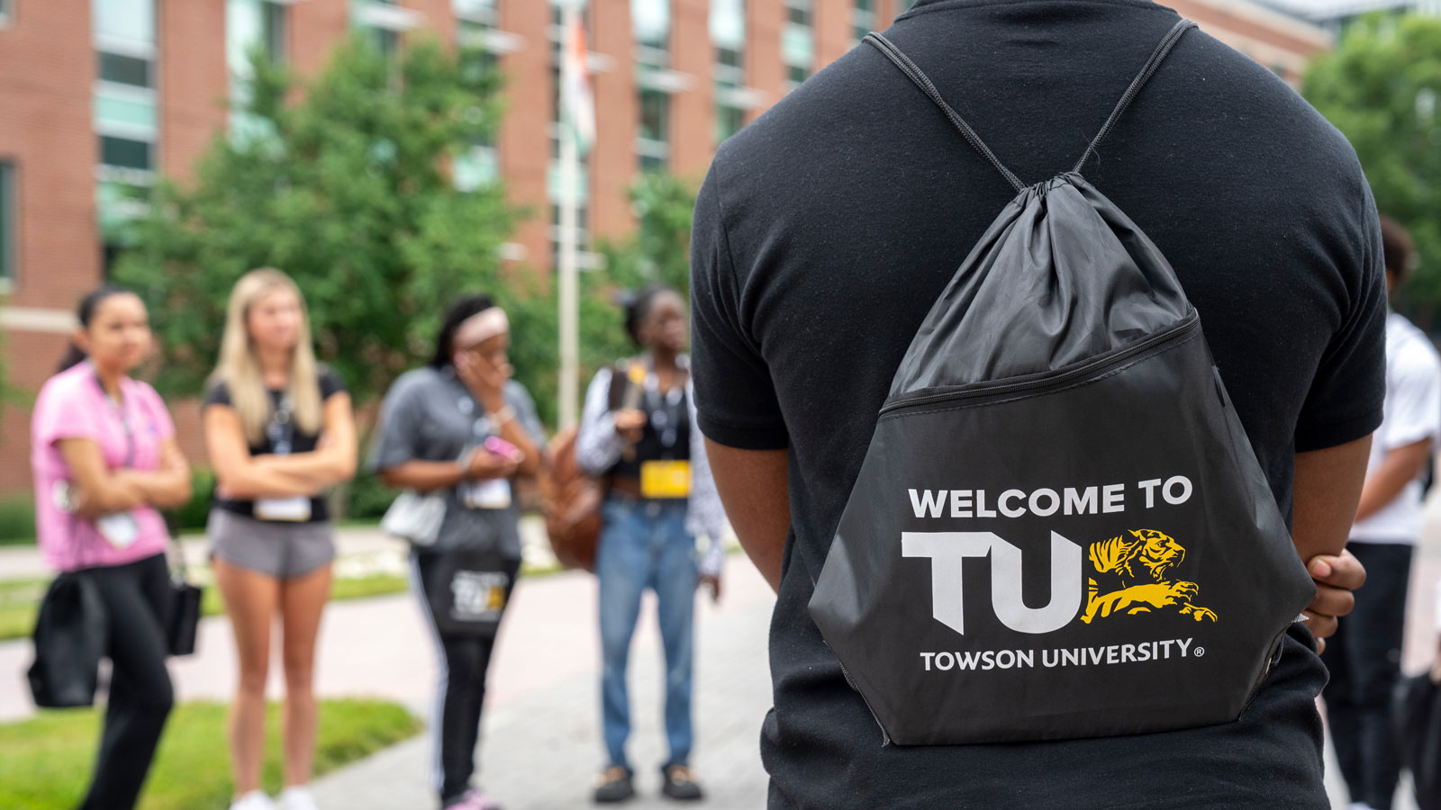 student wearing a TU orientation backpack that says "welcome to TU Towson University"