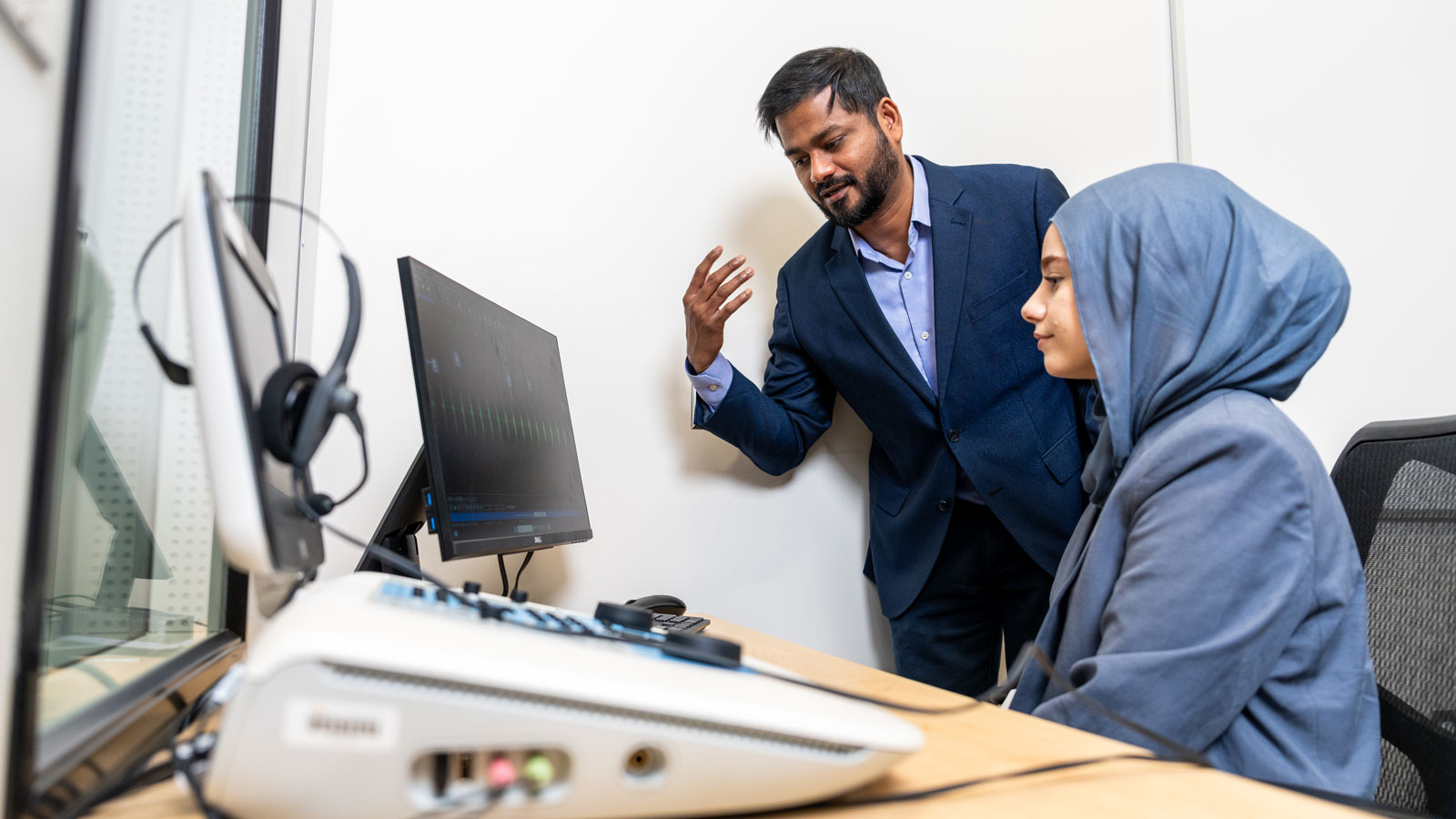 Dr. Patro speaks with student research assistant in one of the Health Professions' building's audiology labs