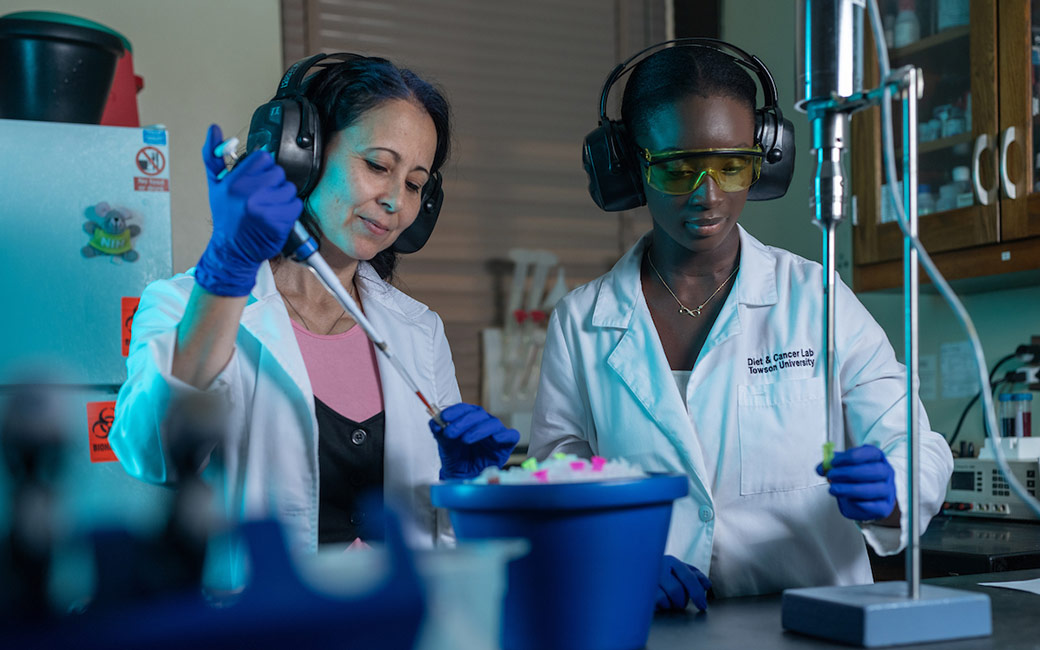 Two women work in lab with blue lighting
