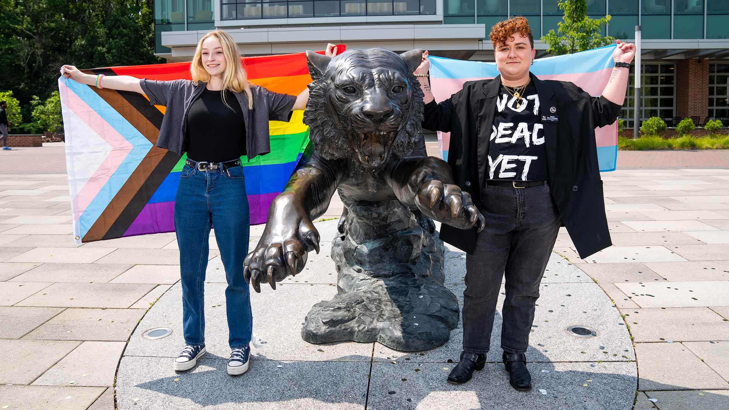 TU students standing in front of a tiger statue with Pride flags