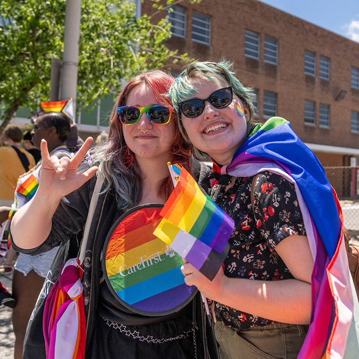 two students smiling with a pride flag