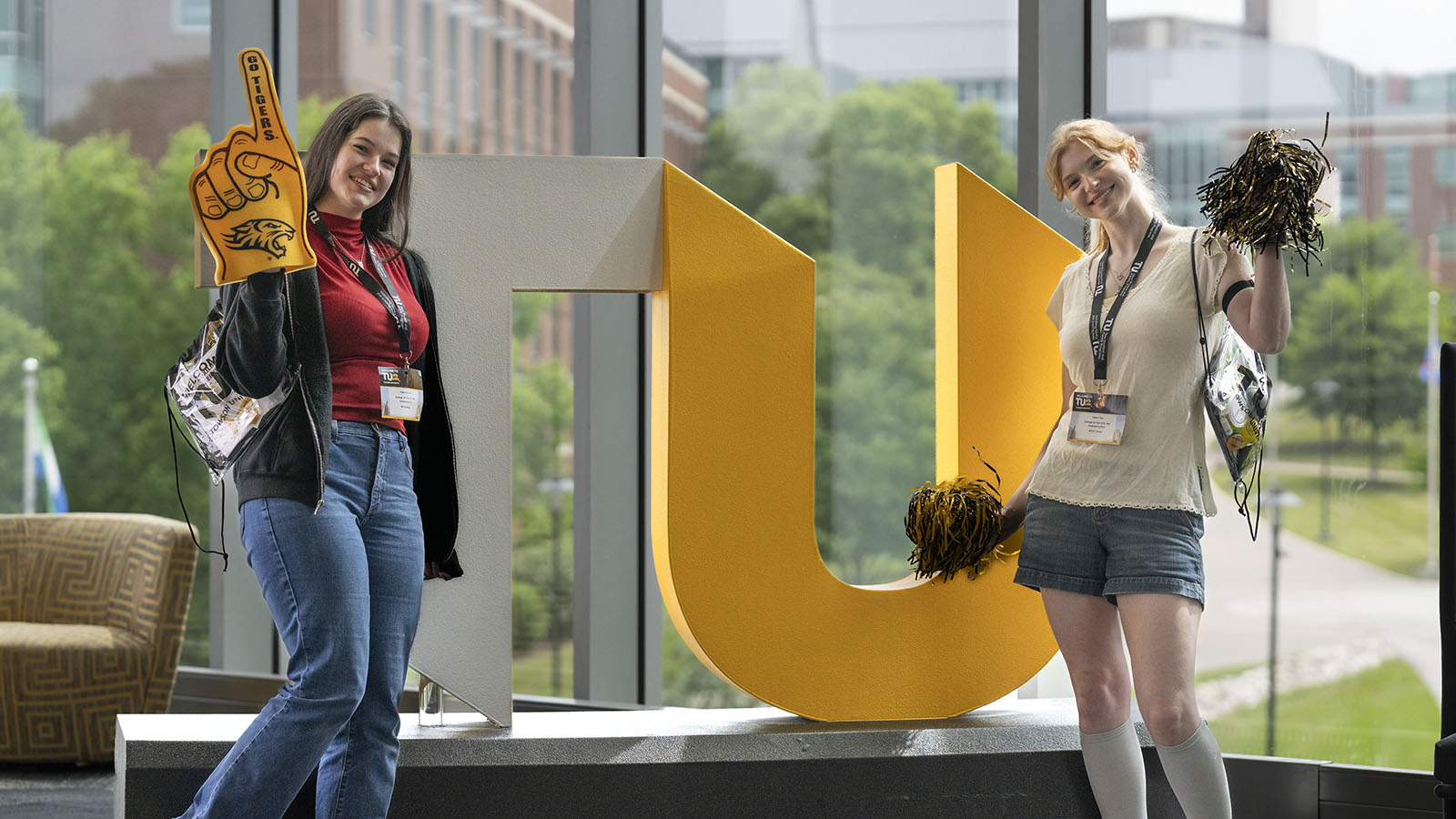 Two students standing in front of TU logo