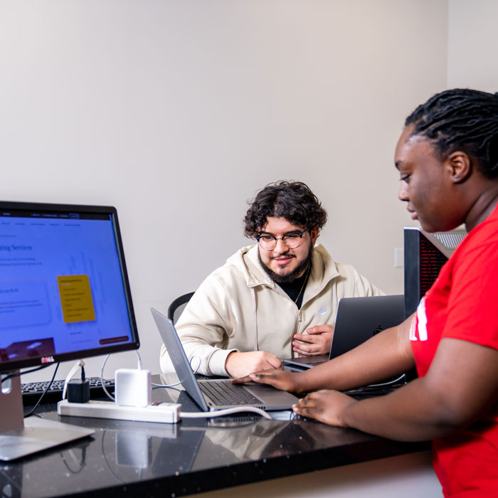 A student employee at the Technology Support Desk assists a student with a tech question
