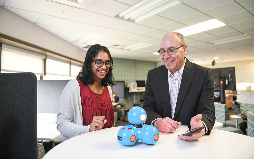 two people with small robot in lab